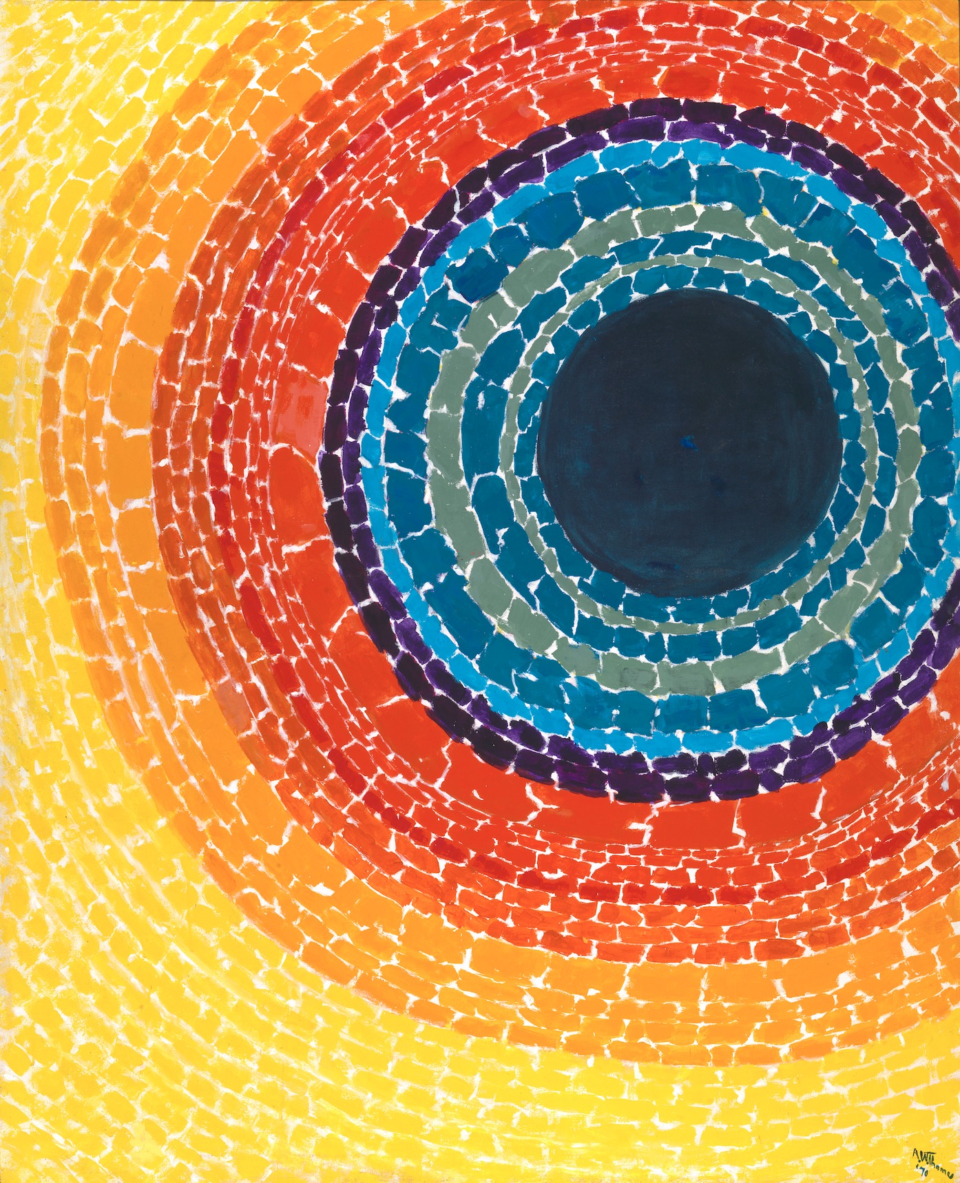An abstract painting by Alma Thomas featuring concentric, circular rings of vibrant color radiating outward from a large, solid dark blue circle positioned in the upper right. Moving outward from the center, the concentric bands transition through shades of teal, deep blue, purple, bright red, orange, and finally a broad field of sunny yellow that fills the left and bottom edges of the canvas.