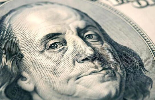 A zoomed in photo of Benjamin Franklin's face on the 100 dollar bill.
