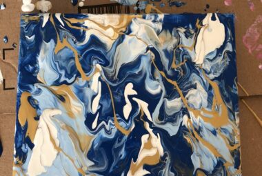 Fluid painted canvas showing a marbling affect with blues, whites and golds.