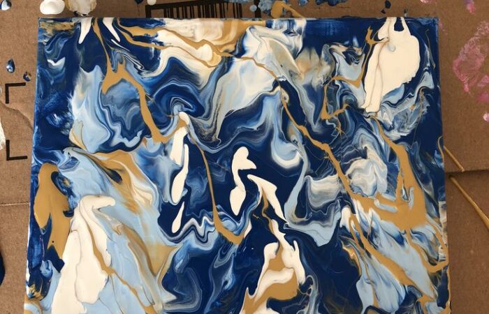 Fluid painted canvas showing a marbling affect with blues, whites and golds.