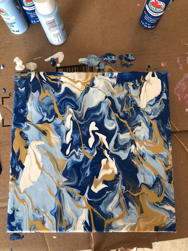 Fluid painted canvas showing a marbling affect with blues, whites and golds.