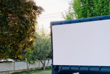 A black blowup screen setup in a backyard surrounded by trees