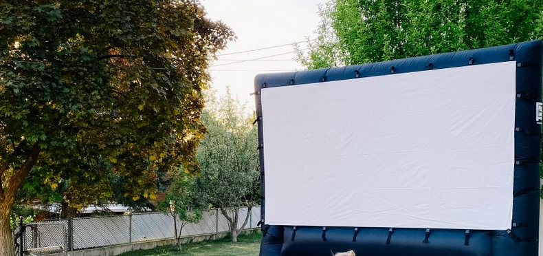 A black blowup screen setup in a backyard surrounded by trees