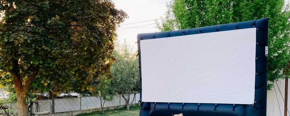 A black blowup screen setup in a backyard surrounded by trees