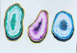 Three cracked open geodes. One is green, purple and blue.