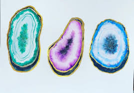 Three cracked open geodes. One is green, purple and blue.