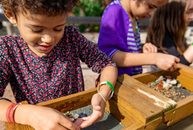 Two children sifting through dirt to locate rocks and gems.