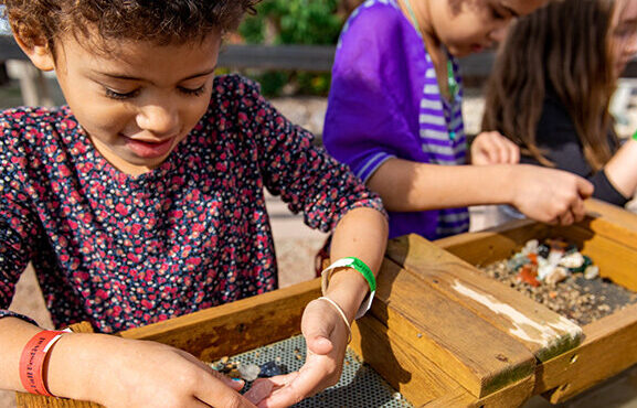 Two children sifting through dirt to locate rocks and gems.