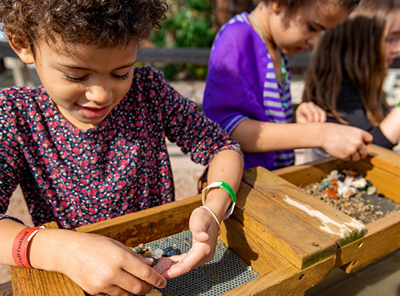 Two children sifting through dirt to locate rocks and gems.
