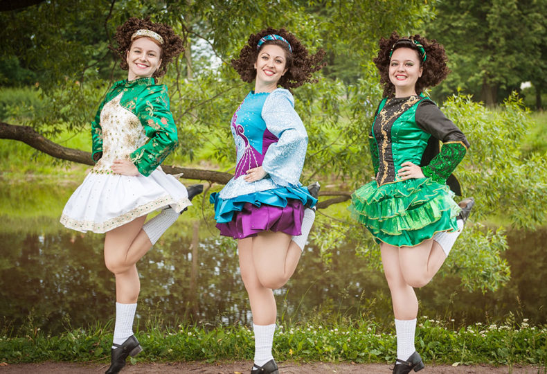 three women in traditional Irish step dresses dancing